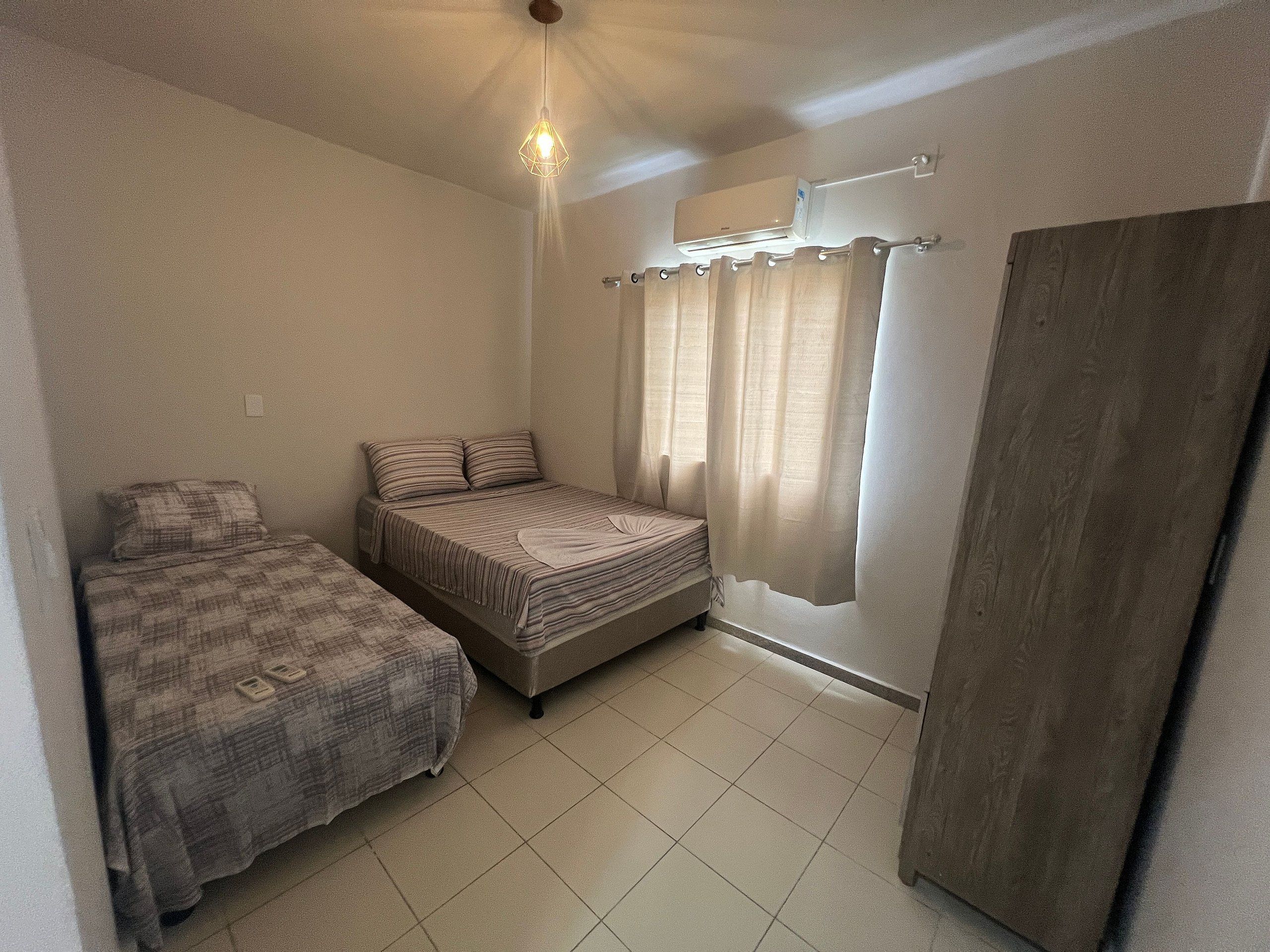 Un alojamiento pequeño, de una sola habitación, con una cama, una mesita de noche y una lámpara colgante.