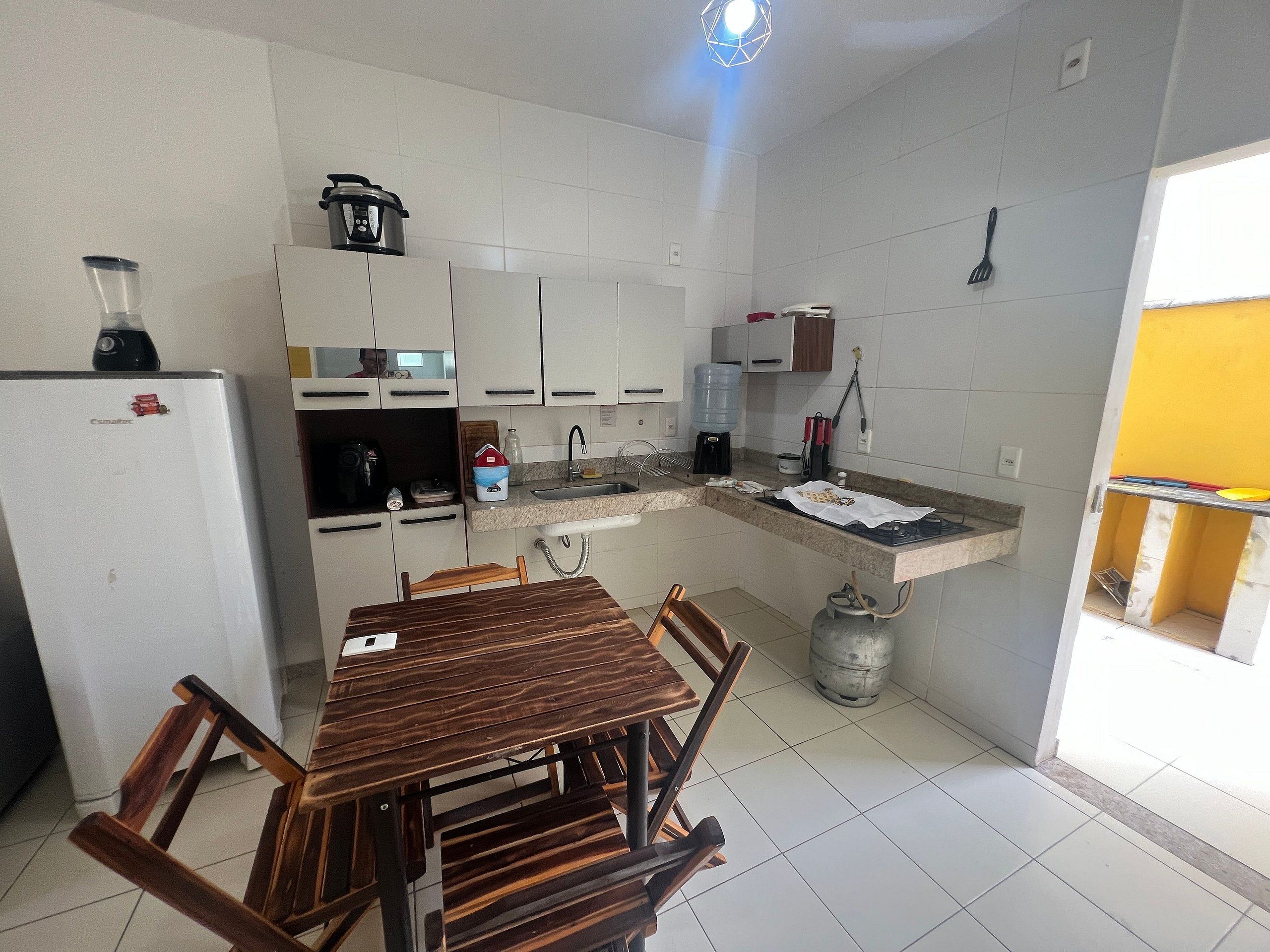A compact kitchen with white cabinets, a built-in gas stove, a sink, and a refrigerator.