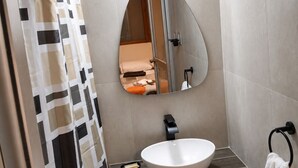 Een badkamer met een wit wastafel, een spiegel, een douchegordijn en een handdoekhouder.