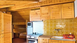 Una cucina compatta con mobili in legno, un fornello, forno e frigorifero.