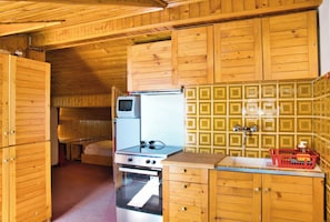 A compact kitchen with wooden cabinets, a stove, oven, and a refrigerator.