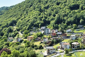 A hillside village with residential buildings, a road, and a soccer field.
