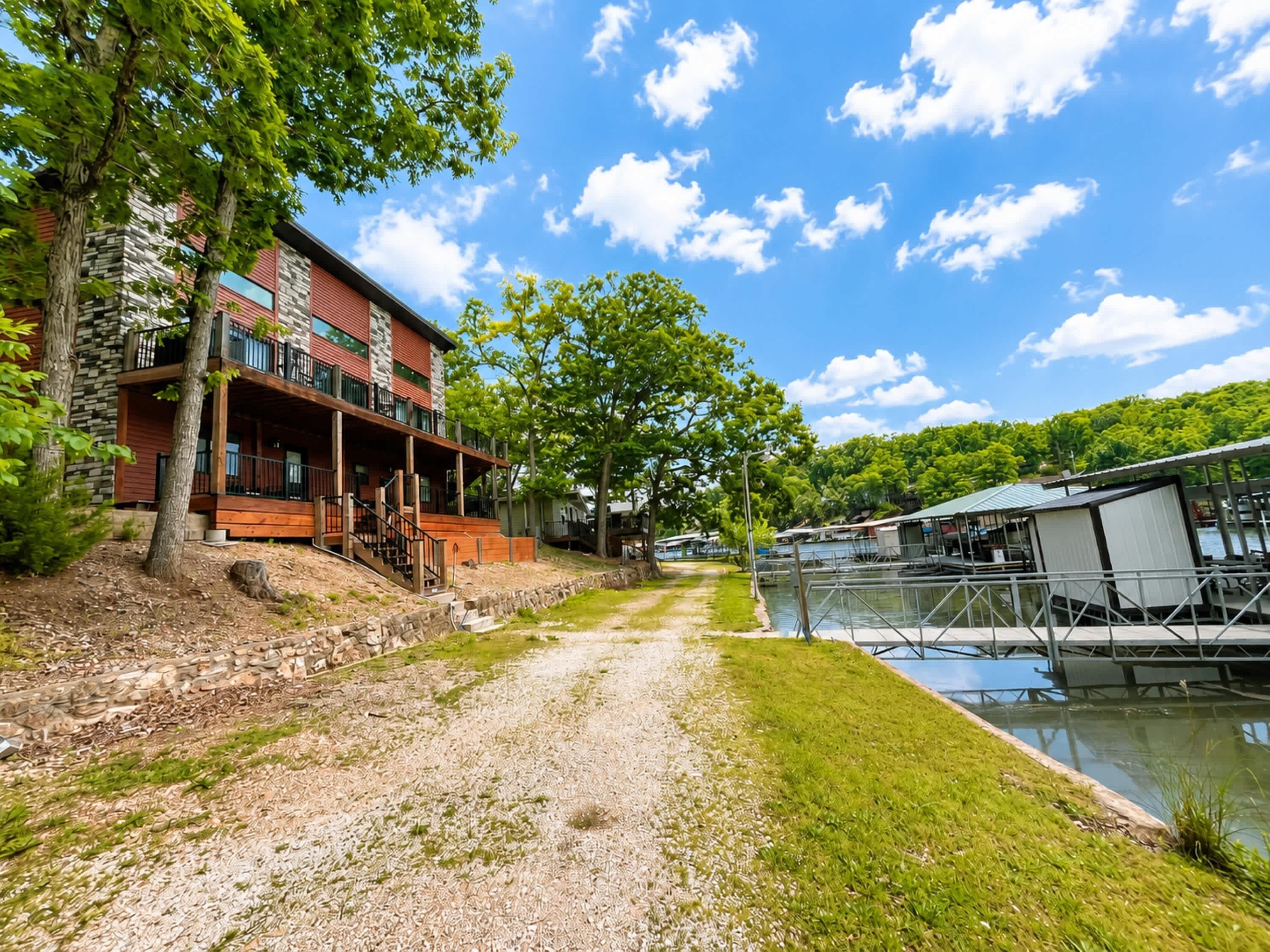 A modern building with a stone facade, a wooden deck, and a view of a water body.