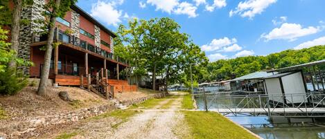 A modern building with a stone facade, a wooden deck, and a view of a water body.