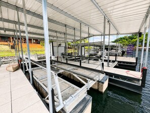 A covered outdoor area with metal structures, a dock, and a water body. - Five Arrows Lakehouse With Dock (Rocky Mount)