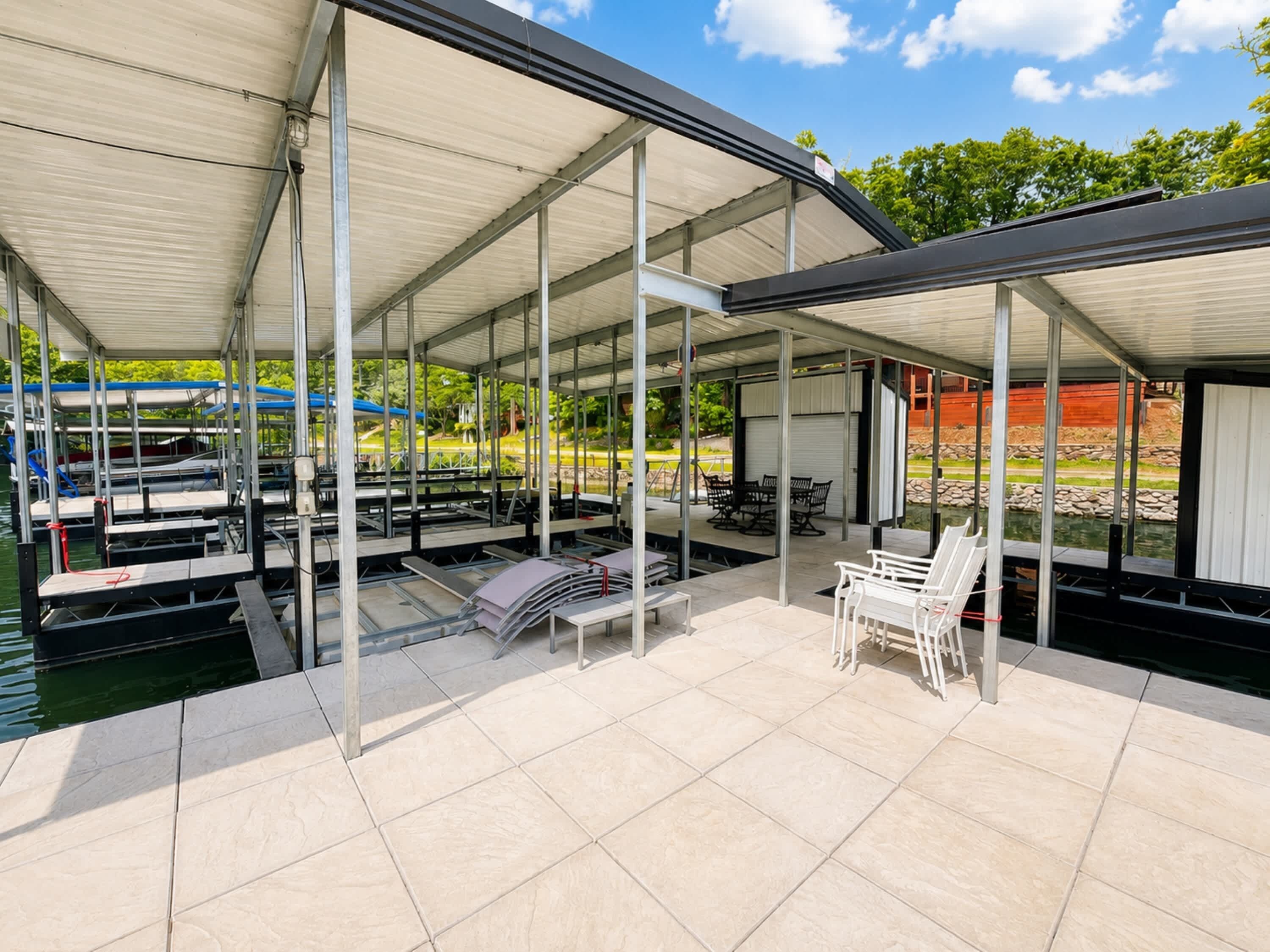 A covered outdoor area with a pool, seating, and a view of the water.