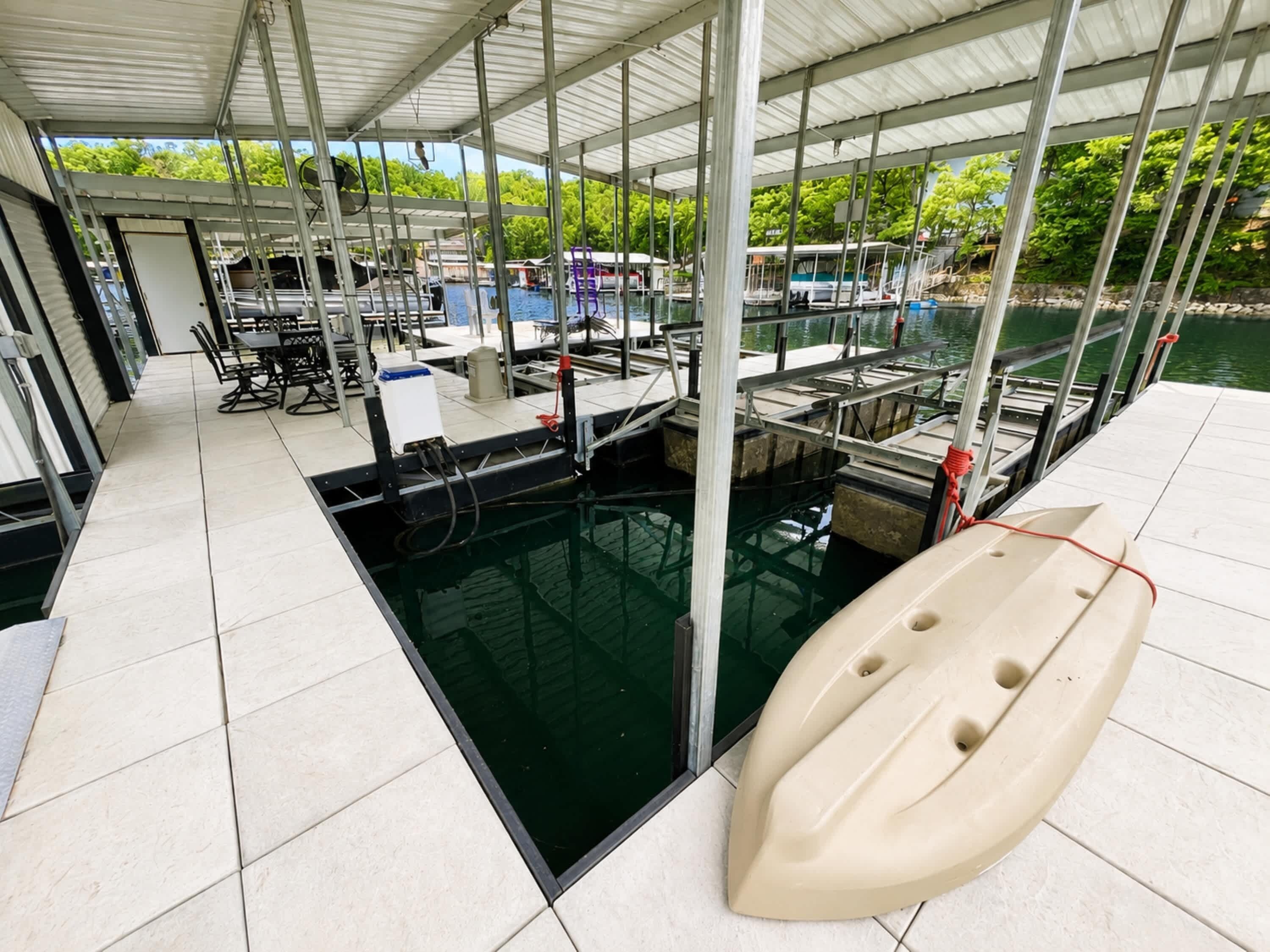 A covered swimming pool area with a boat, a table, and chairs.
