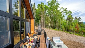 Eine Terrasse mit Esstisch, Grill und Whirlpool.