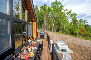 Eine Terrasse mit Esstisch, Grill und Whirlpool.