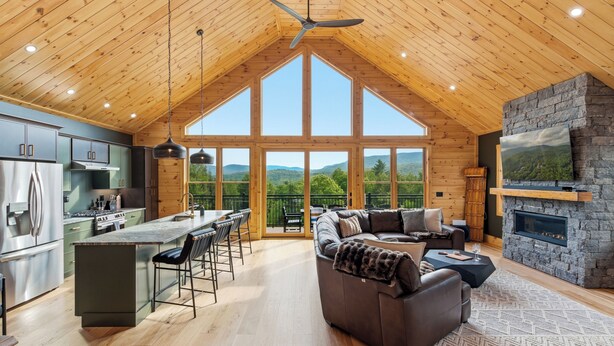 Ein geräumiges Loft mit hohen Decken, einer Küche mit modernen Geräten, einer gemütlichen Sitzecke mit Kamin und großen Fenstern mit Blick ins Freie.