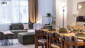 Een moderne woonkamer met een eethoek, een bank, een salontafel en een vloerlamp.