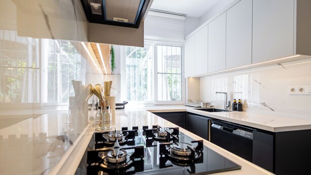 Een moderne keuken met een centraal eiland, zwarte apparaten en grote ramen.