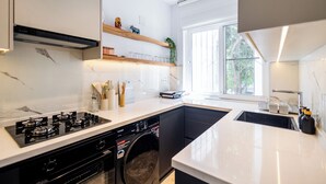 Een moderne keuken met een ingebouwde wasmachine en droger, een groot raam en een wit aanrecht.