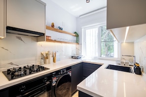 A modern kitchen with a built-in washer and dryer, a large window, and a white countertop.