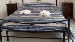 A bed with a striped bedspread, two rolled towels, a painting of a dock, and two bedside tables with candles. - Cozy, quiet for families. Pets allowed (Perugia)
