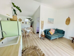 A modern living room with a teal sofa, a dining area with a white table and chairs, and a kitchen with a green sink. - Magnificent, peaceful ground floor villa with unobstructed view. Ideal for families (Sainte-Maxime)