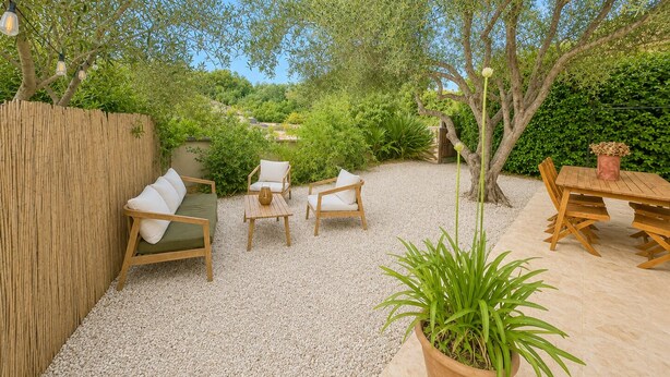 Eine Terrasse mit Gartenmöbeln, einem Holztisch und einem Blumentopf.