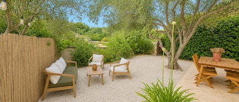 Un patio con mobiliario exterior, una mesa de madera y una planta en maceta.