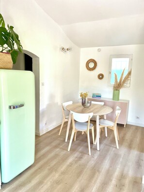 A dining area with a round table, four chairs, a green refrigerator, and a window with a view. - Magnificent, peaceful ground floor villa with unobstructed view. Ideal for families (Sainte-Maxime)
