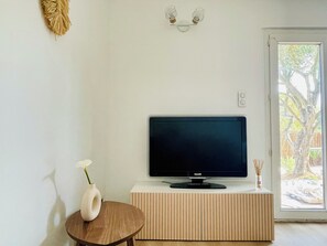 A modern living room with a flat-screen TV on a wooden cabinet, a small round table with a vase, and a decorative wall piece. - Magnificent, peaceful ground floor villa with unobstructed view. Ideal for families (Sainte-Maxime)