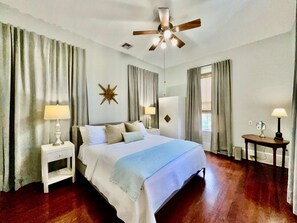 Ein Hotelzimmer mit Bett, Nachttisch, Deckenventilator, einer Sterne-Dekoration und einem Fenster mit Vorhängen.