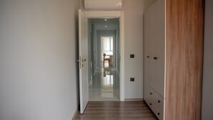 A hallway with a wooden floor, a wardrobe, and a door leading to another room. - Santana Suit (Arsin)
