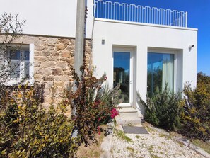 Un bâtiment moderne avec des murs en pierre, de grandes portes vitrées et un balcon.