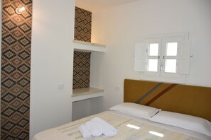 Una habitación de hotel con cama, cabecera, ventana y pared con estampado.