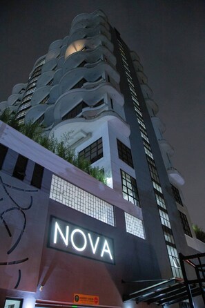 Ein Gebäude mit einem auffälligen 'NOVA'-Schild, einem modernen architektonischen Design und Balkonen, sowie einem gut sichtbaren Eingang.