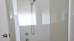 Cabina doccia con pareti in vetro, soffione a mano e rubinetto montato a parete.