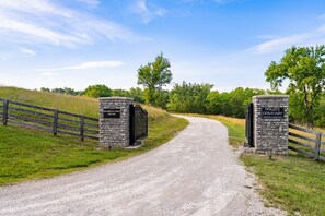 A gravel road leading to a private driveway with stone pillars labeled 'Bourbon Trail Escape' and 'Private Driveway.'