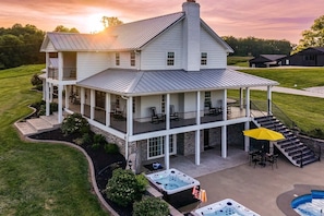 A large house with a covered porch, multiple levels, and outdoor hot tubs.