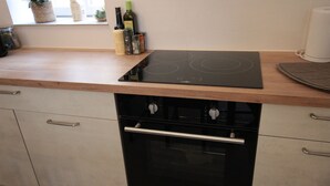 A kitchen with a black stove top oven, a built-in dishwasher, and a wooden countertop.