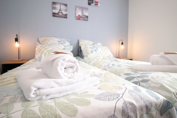 A hotel room with a neatly made bed, two bedside lamps, and a wall with framed pictures.