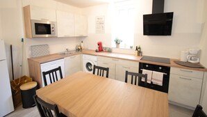 A compact kitchen with a microwave, oven, sink, and a dining area with a table and chairs. - Les Loges de Véro RDC - 5 min from Verdun, private parking, motorcycle garage, air conditioning. (Thierville-sur-Meuse)