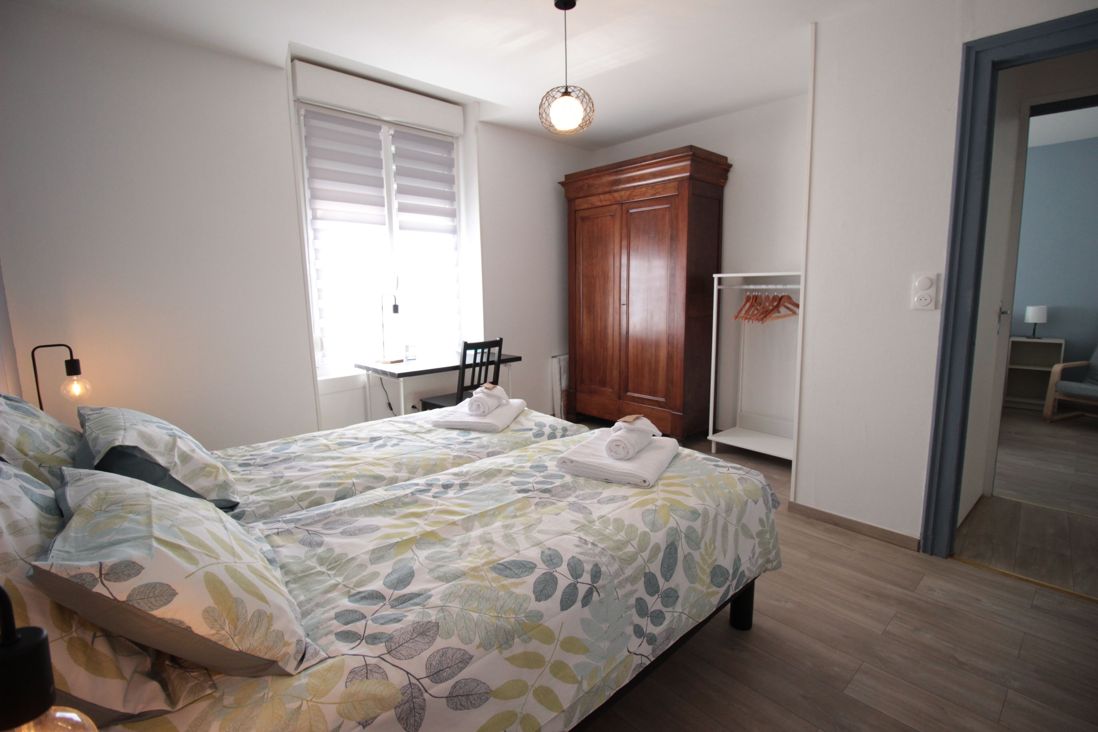 Ein Schlafzimmer mit zwei Betten, einem Schrank, einem Schreibtisch und einem Stuhl.