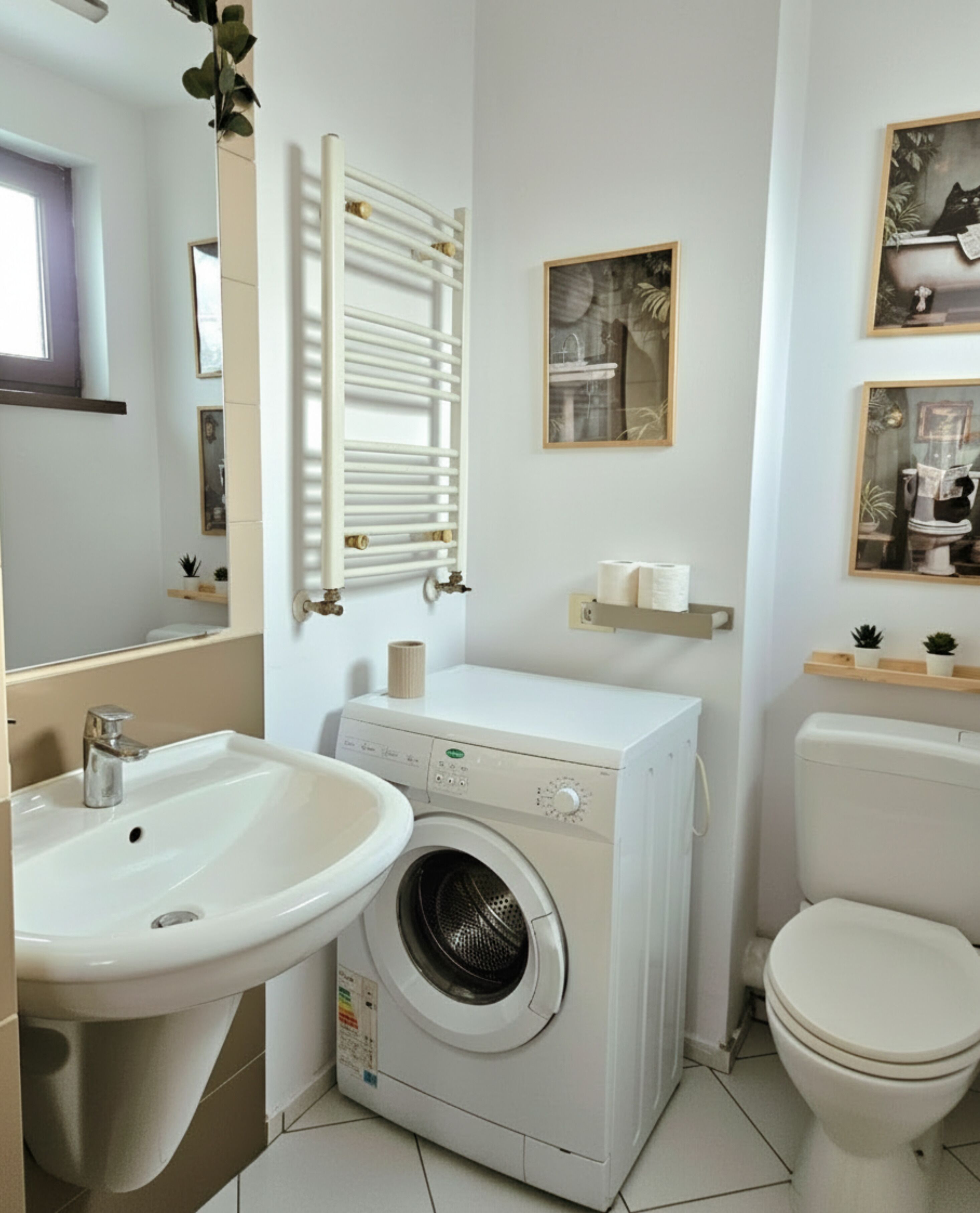 Un baño pequeño con lavamanos, lavadora, inodoro y espejo con barra para toallas.