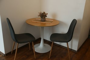 Ein kleiner runder Tisch mit zwei Stühlen, einem Blumentopf und einer Tischmatte mit Streifen.