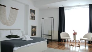 A modern hotel room with a bed, a small table, two chairs, a hanging chair, and a large window with curtains. - Mosilor Residence (București)