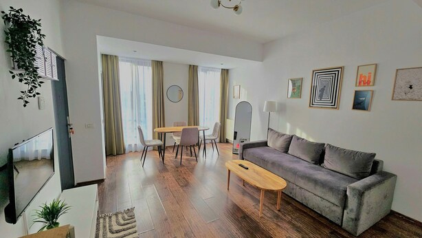 A modern living room with a sofa, coffee table, and dining area. - Mosilor Residence (București)