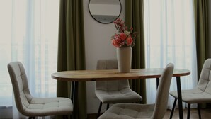 A room with a round wooden table, four chairs, a vase with flowers, a round mirror on the wall, and sheer curtains. - Mosilor Residence (București)