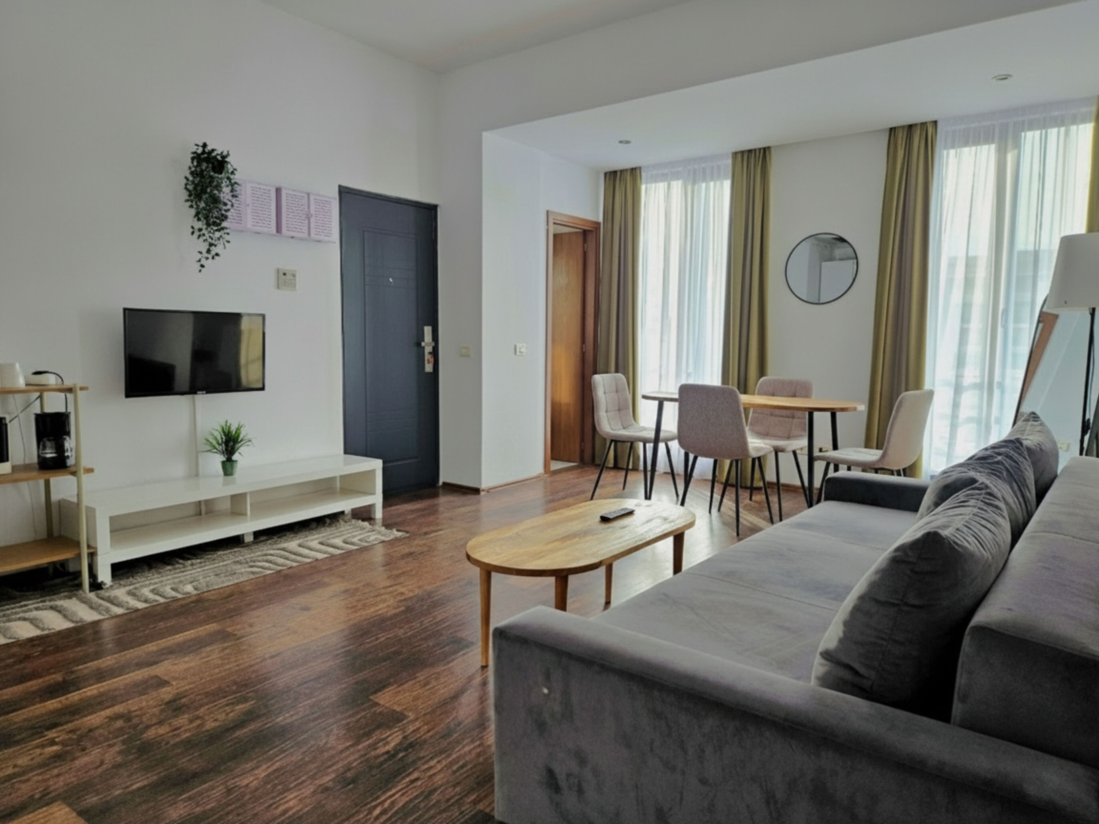 Un salon moderne avec un canapé, un téléviseur, un coin repas avec des chaises et un plancher en bois.