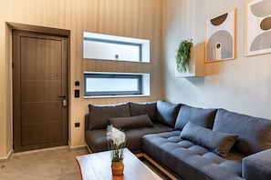 A modern living room with a sofa, a coffee table, and a door. - Noemi City Loft 3, Loft (Iraklio)