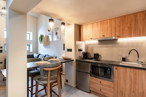 A modern kitchen with wooden cabinets, a stainless steel refrigerator, and a built-in oven. - Noemi City Loft 3, Loft (Iraklio)