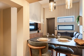 A dining area with a marble table, upholstered chairs, and pendant lighting. - Noemi City Loft 3, Loft (Iraklio)