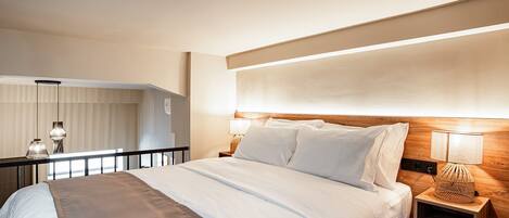 A hotel room with a large bed, bedside lamps, a wooden headboard, and a view of the room's interior.