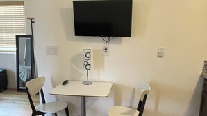 A dining area with a table and two chairs, a wall-mounted TV, and a decorative sun-like object. - Cozy 1-bedroom studio in rural Tucson with AC,beautiful view (Tucson)