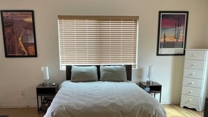A bedroom with a bed, a ceiling fan, a window with blinds, a nightstand, a dresser, and two framed pictures on the walls. - Cozy 1-bedroom studio in rural Tucson with AC,beautiful view (Tucson)