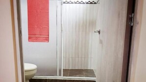 A bathroom with a toilet, shower, and a red towel hanging on the wall. - Cocoloco's Lodge - Family Bungalow (El Valle)