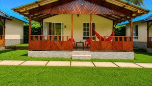 A two-story building with a covered porch, a red hammock, and a clear blue sky. - Cocoloco's Lodge - Family Bungalow (El Valle)